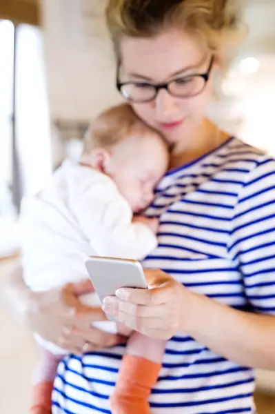 Mãe Segurando Pequeno Bebê Olhando Para Telefone Celular — Fotografia de Stock