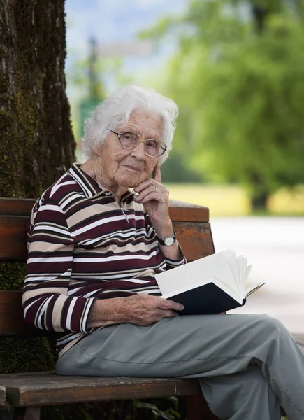 Senior Kobieta Siedzi Ławce Czytanie Książki — Zdjęcie stockowe