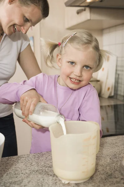 Madre e figlia versando latte — Foto Stock
