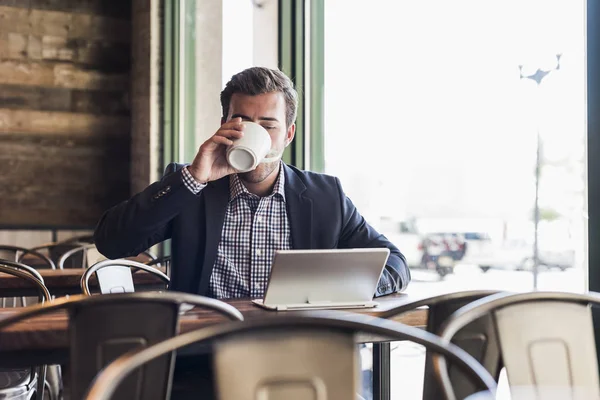 Homme d'affaires buvant du café et utilisant une tablette dans un café — Photo de stock