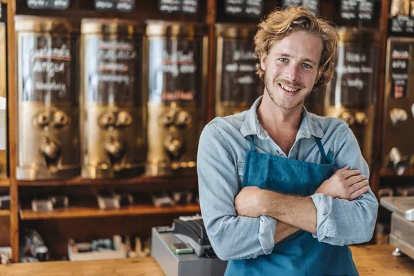 Porträt eines lächelnden Kaffeerösters, der mit verschränkten Armen im Geschäft steht — Stockfoto