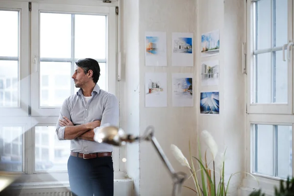 Thoughtful man looking out of window in office — Stock Photo