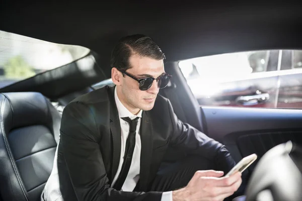 Businessman in car using cell phone — Stock Photo