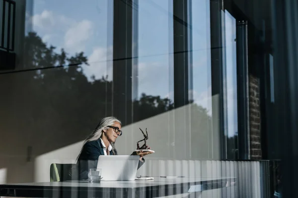 Femme d'affaires assise au bureau et regardant la sculpture — Photo de stock