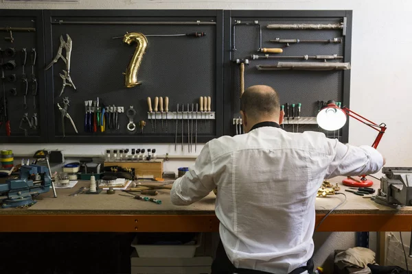 Instrument maker dismounting saxophone during repair — Stock Photo