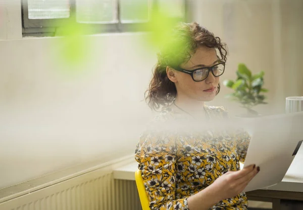 Jeune femme d'affaires lisant un document au bureau — Photo de stock