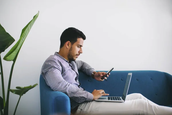 Homme d'affaires assis sur le canapé dans le bureau en utilisant un ordinateur portable — Photo de stock