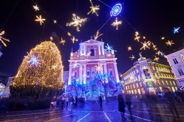 Ljubljana, Slovenya - 21 Aralık 2017: Advent Aralık gece alacakaranlıkta Ljubljana'nın şehir merkezinde Noel dekorasyon aydınlatma ile. Nehir Ljubljanica, üçlü köprü, Preseren kare ve Fransisken Kilisesi duyuru.