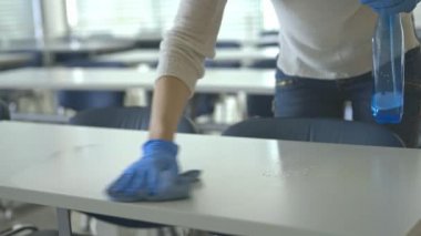 Karantina döneminde temizlikçi kadın okul sınıfındaki masaları dezenfekte ediyor, Covid-19