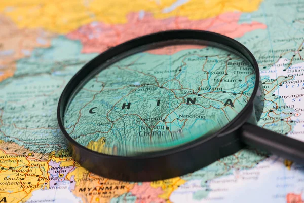 Map of china through magnifying glass on a world map.