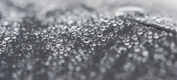 Closeup gedetailleerde weergave van regendruppels op een stof, een achtergrond. — Stockfoto