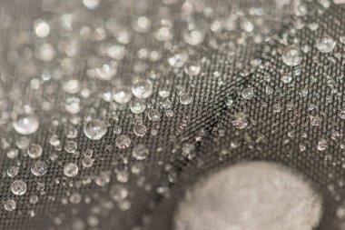 Closeup yağmur damlaları görünümünü kumaş, bir arka plan üzerinde ayrıntılı.