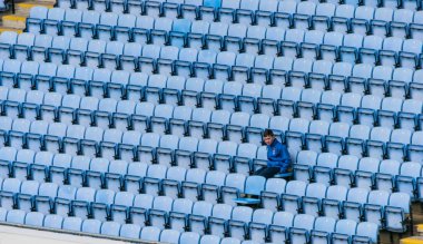 Tek başına oyun izlerken bir çocuk ile mavi plastik stadyum koltuklar, satırlar.