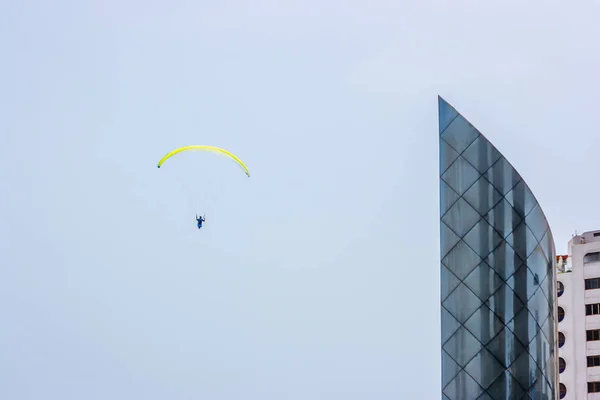秘鲁利马上空的一座摩天大楼旁边的黄色滑翔伞 — 图库照片
