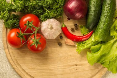 yuvarlak ahşap tahta üzerinde çiğ sebze.