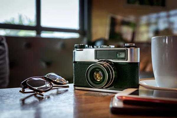 Винтажная камера с чашкой кофе, очками и смартфоном на тарелке — стоковое фото