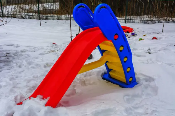 Giocattoli per bambini coperti di neve nel cortile di una casa privata — Foto Stock