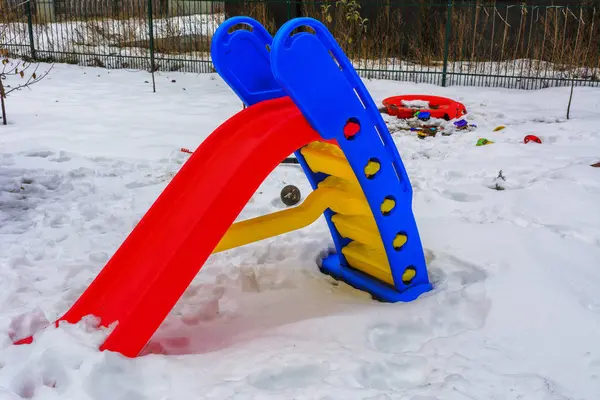 Giocattoli per bambini coperti di neve nel cortile di una casa privata — Foto Stock