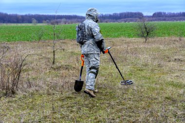 Adamla bir aygıt üzerinde bir kürekle hazineleri bulmak için bes