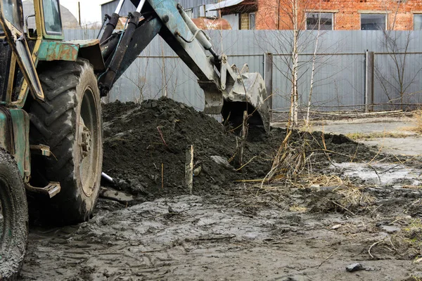 Een oude Sovjet-Unie trekker graaft en ladingen afvalstoffen steen verwerking in de buurt van — Stockfoto