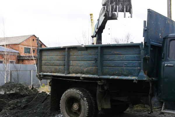 Stary ciągnik radziecki digs i ładuje odpadów obróbki w pobliżu kamienia — Zdjęcie stockowe