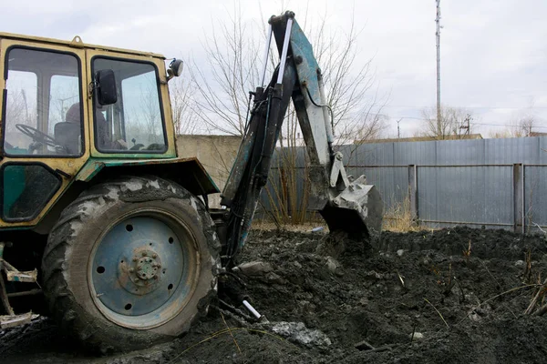 Un viejo tractor soviético excava y carga residuos de procesamiento de piedra cerca —  Fotos de Stock