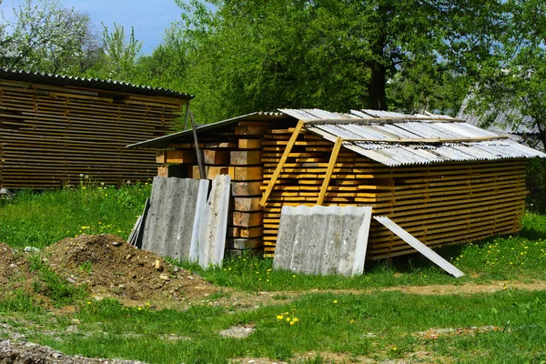 Σανίδες στοιβάζονται σε μια αυλή κοντά σε ένα ιδιωτικό σπίτι με το συγκρότημα — Φωτογραφία Αρχείου