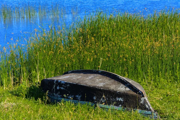 Старий дерев'яний човен лежить на березі красивого озера — стокове фото