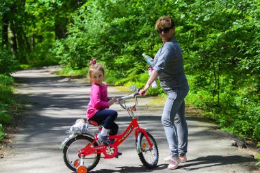 Dabushka ve torunu şehir parkta Bisiklete binmek. 