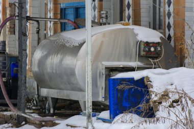 Kışın beyaz kar çerçevede bir bir terk edilmiş ve yıkılan fabrika süt toplamak için büyük bir eski tank. Yıkım ve vandalizm. Ukrayna.
