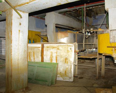 Duvara karşı bir terk edilmiş ve yıkılan fabrika süt toplamak için a büyük eski sökülmüş ve paslı tank. Yıkım ve vandalizm. Ukrayna.