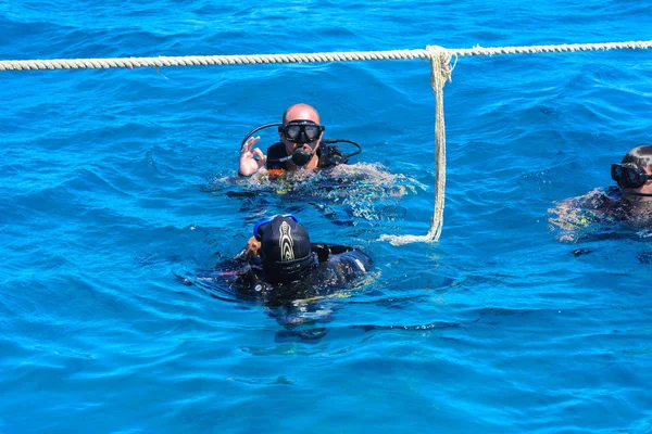 Dalgıçlar açık ve turkuaz Kızıldeniz daldırma güzel mercan ve renkli balık üzerinde. Öğretmen öğrenci suya daldırma kuralları öğretir.. 