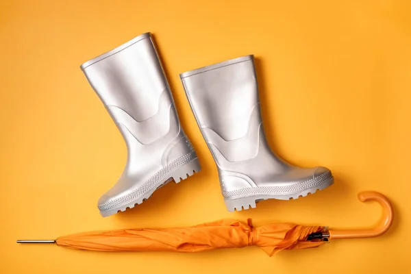 Turuncu zemin üzerine yukarıda görünümü şemsiye ve şık gümüş gumboots. Üstten görünüm. Düz yatıyordu.