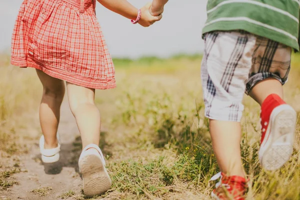 Мальчик и девочка держатся за руки и идут по следу — стоковое фото
