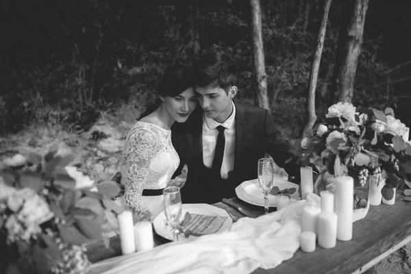 Married couple posing at party table in forest