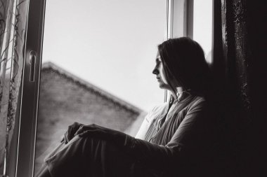 Pencerede oturan siyah beyaz bir kızın fotoğrafı.
