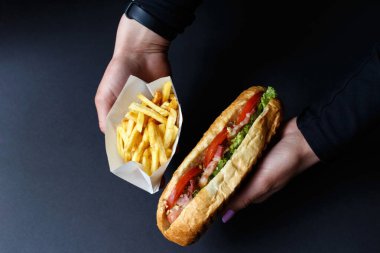 Siyah arka planda sosisli ve patates kızartması..