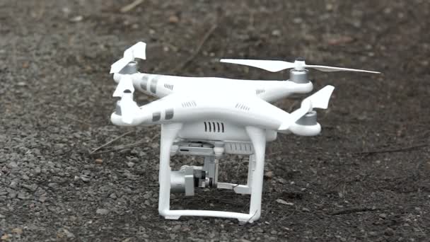 Ένα drone να στέκεται στο έδαφος αρχίζει να περιστρέφεται έλικες. — Αρχείο Βίντεο