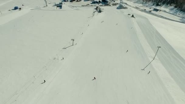 Кілька людей катаються на лижах і сноуборді на схилі снігу . — стокове відео