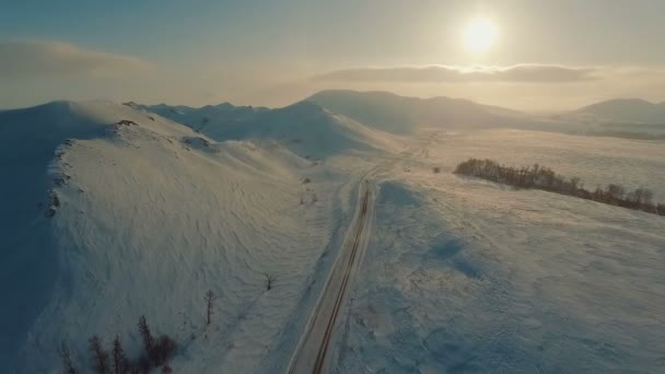 Кілька автомобілів, що їздять по крижаній дорозі в сутінках біля гір . — стокове відео