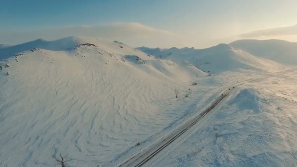 Varios coches que conducen por carretera helada en el atardecer cerca de las montañas . — Vídeos de Stock