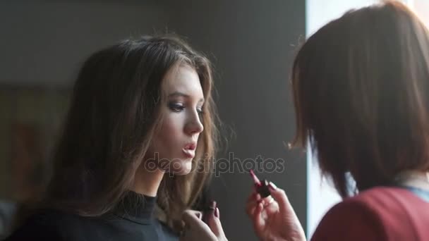 Make up artist doing makeup for model. Lip gloss application