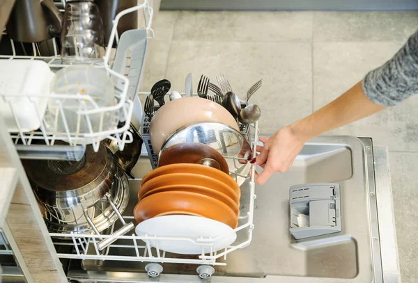 女性は、食器洗い機で汚れた皿をプッシュ. — ストック写真