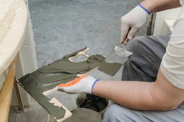 İşçinin yapıştırıcı çini koyar..