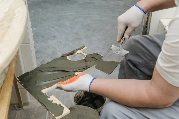 İşçinin yapıştırıcı çini koyar..