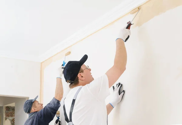 Två arbetare måla en vägg i rummet. — Stockfoto