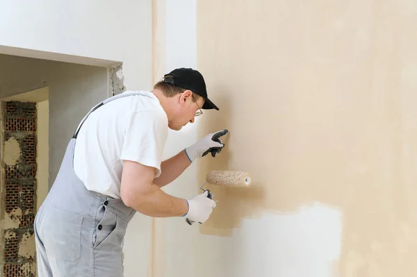 Pintor pinta una pared en la habitación . — Foto de Stock