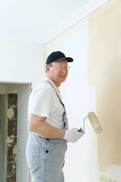 Pintor pinta una pared en la habitación . — Foto de Stock