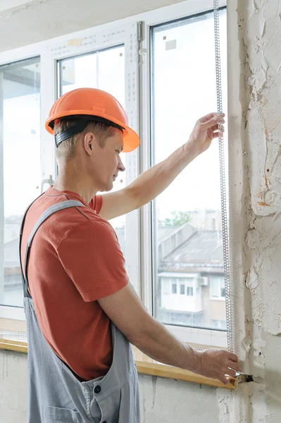 Εργαζόμενος είναι να εγκαταστήσετε μια γωνία διάτρητο αλουμίνιο. — Φωτογραφία Αρχείου