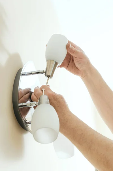 Electrician is instilling a wall lamp. — Stock Photo, Image